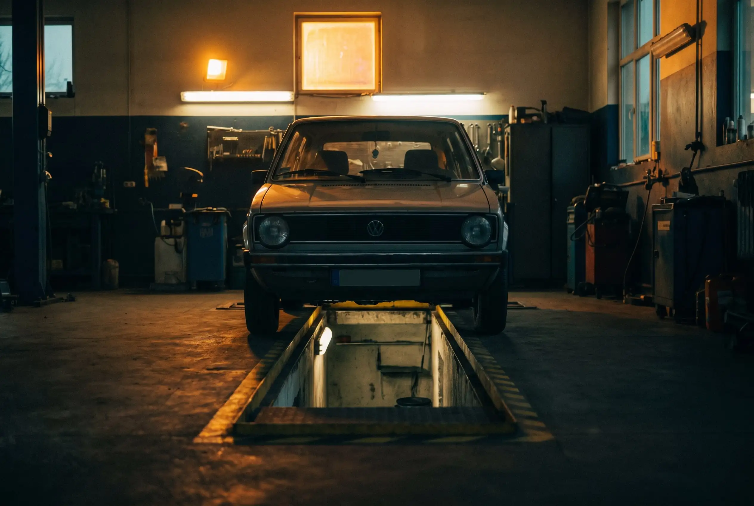 Auto stojące na kołach nad podświetlonym kanałem w ciepło oświetlonym warsztacie